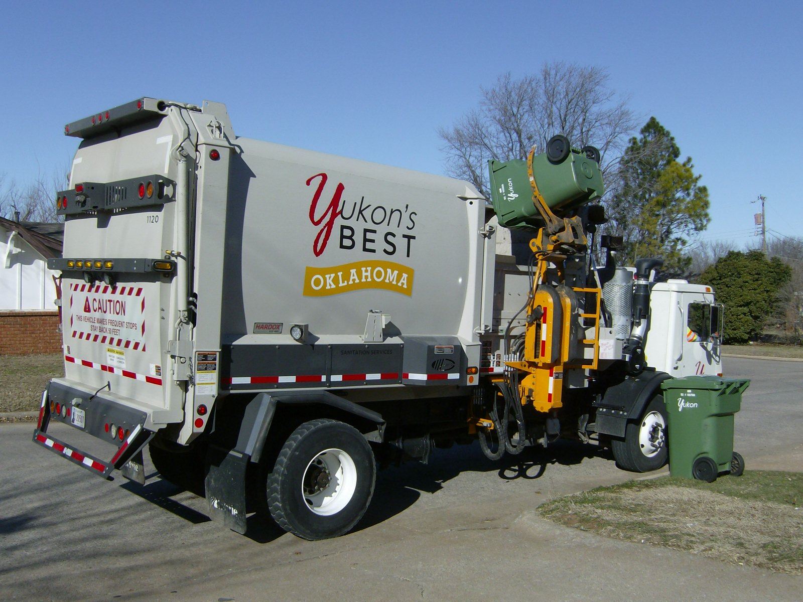 Yukon Dump Truck Picking up a Green Cart