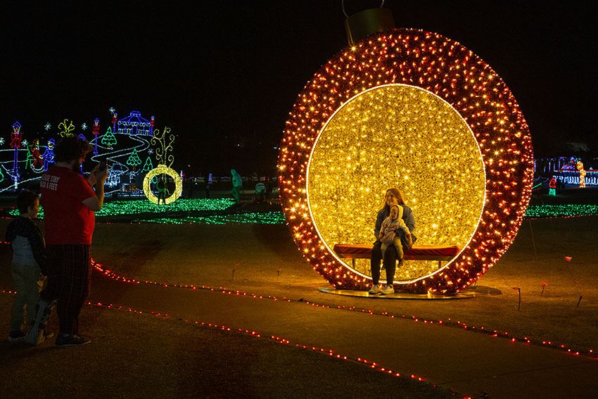 Mother and Child Have Their Picture Taken Inside a Half-Ornament Light Display