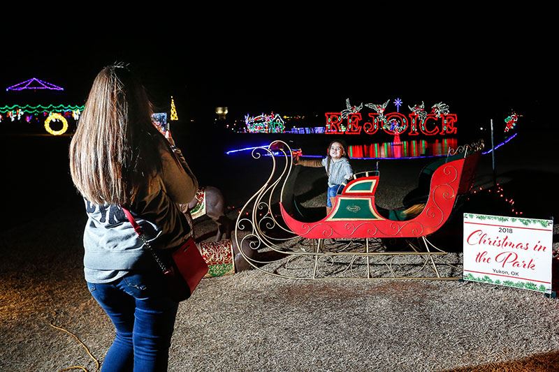 Mother Taking a Picture of Her Daughter in a Santa's Sleigh Display