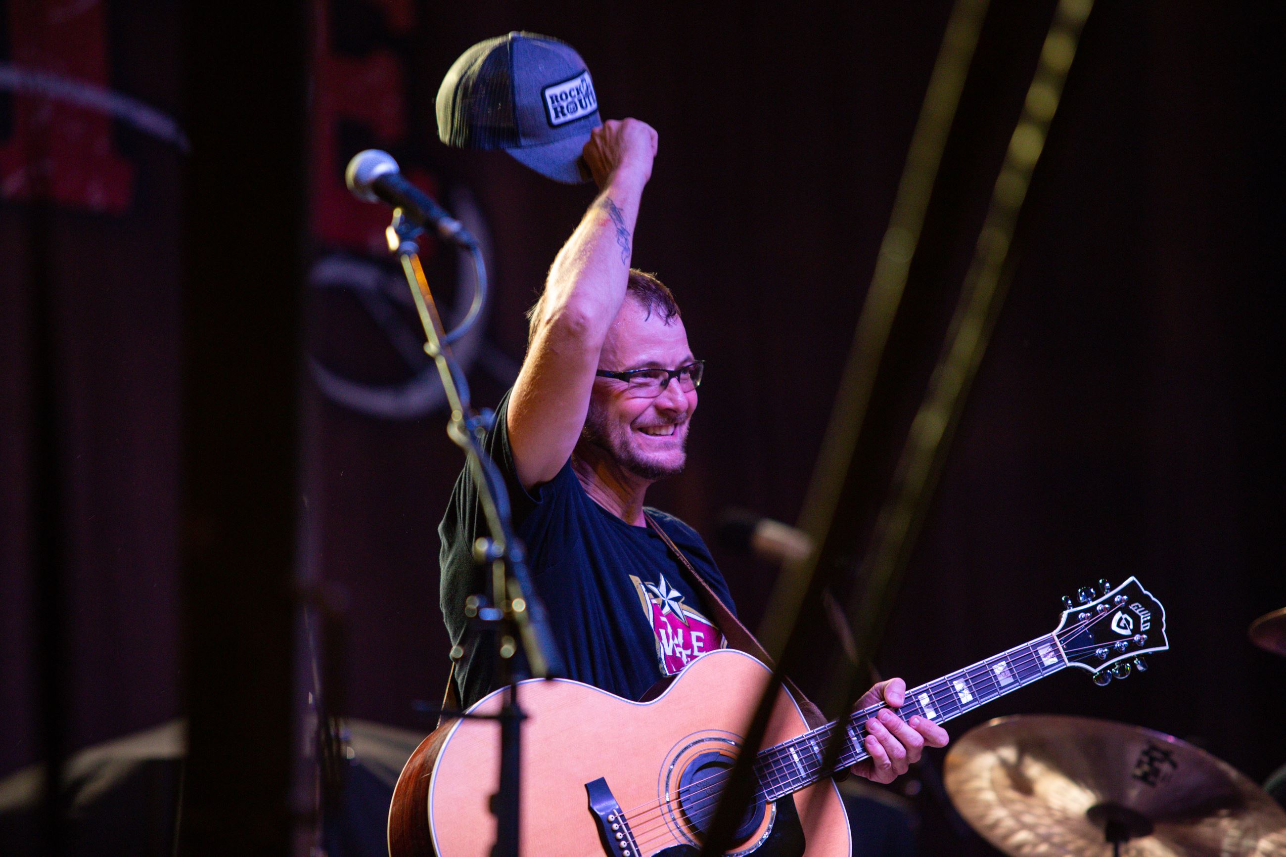 Guitarist Gesturing to the Audience with His Hat