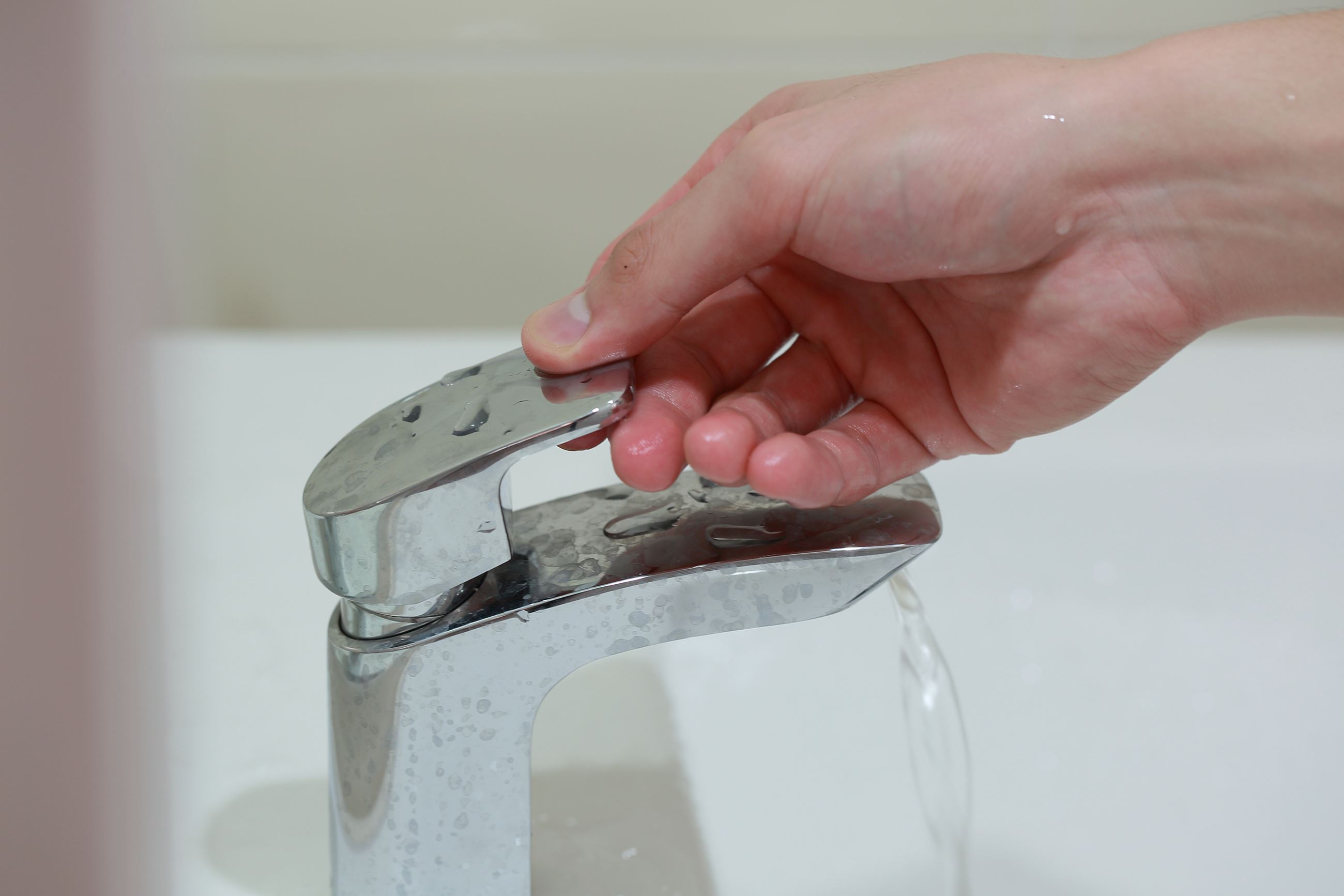 Hand Turning off a Water Faucet